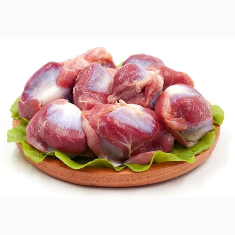 Chicken gizzards on a wooden plate with lettuce, showcasing their rich, meaty texture.